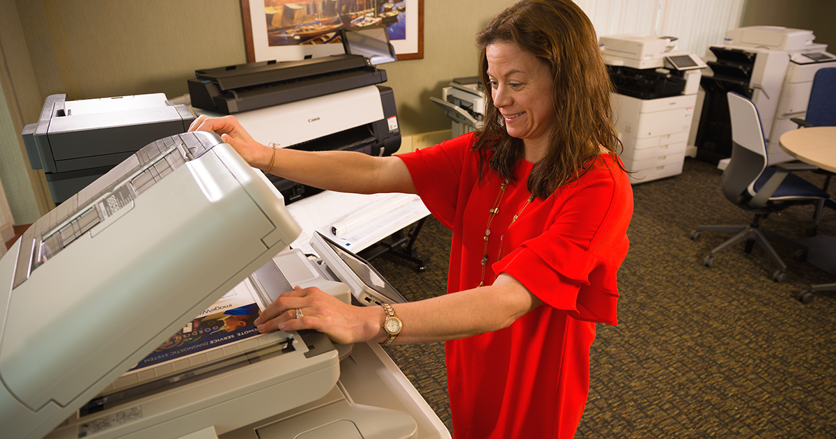 woman scanning paper documents on scanner in office