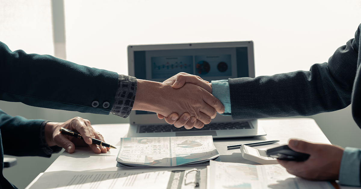 two hands clasped together and shaking at a meeting 