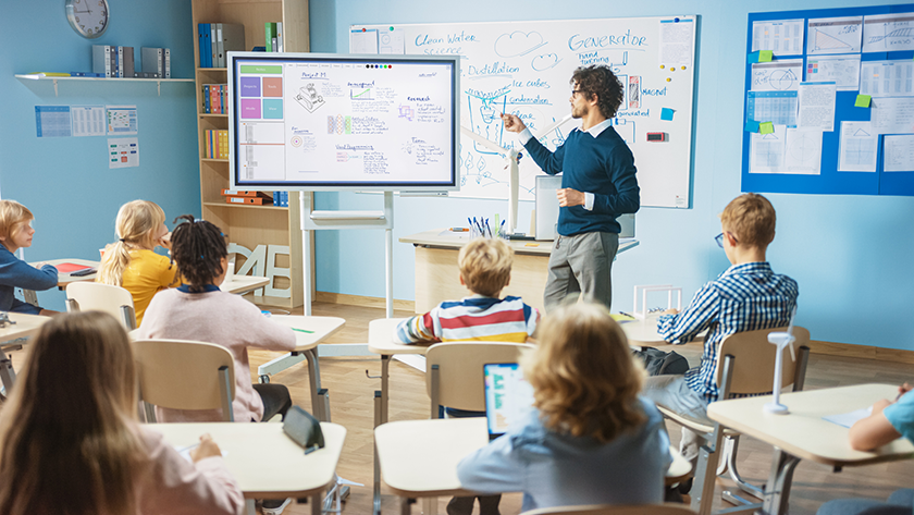 teacher in a classroom teaching with an interactive display